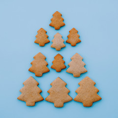 Christmas tree made of homemade shortbread cookies on light blue background. Flat lay, minimal composition. Festive pastry. New Year