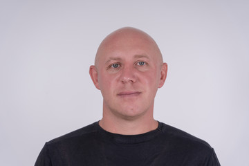 Portrait of middle-aged caucasian bald man looking straight at camera, close up
