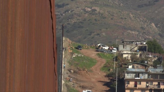medium shot, people walking next to border barrier