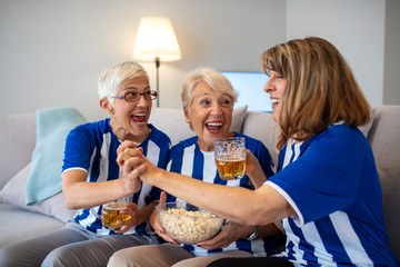 Senior women watching football on TV. Elderly Woman Fans Emotionally Watching Soccer on Tv and celebrating victory at home. Soccer team just scored a goal