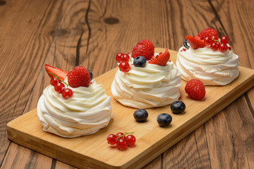 Cakes with berries on the board. Wood background