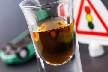 A glass of whiskey, a traffic light and an inverted car. Concept on the topic of drunk driving