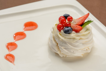 Delicious cake with strawberries and lingonberries on a white plate.