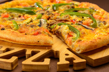 Meat pizza with green pepper on the wooden board. One piece cut off