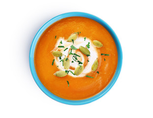 Pumpkin soup with cream and seeds isolated on white background.