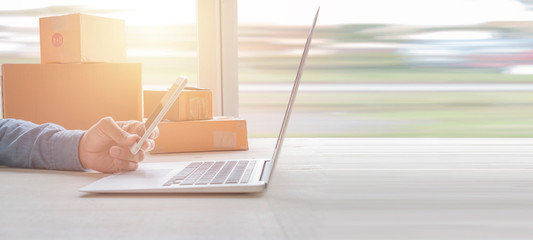 Laptop computer at workplace of start up, small business owner. cardboard parcel box of product for...