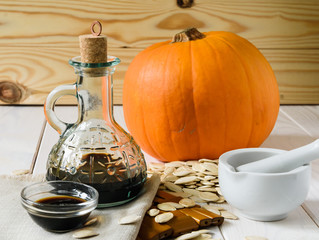 pumpkin oil with pumpkin and pumpkin seeds on a light wooden background