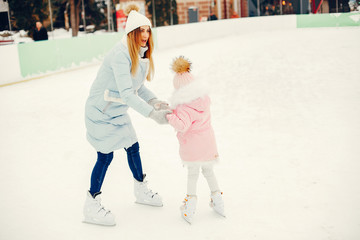 Family in a winter park. Mother with daughter in a ice arena