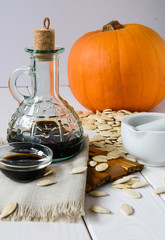 pumpkin oil with pumpkin and pumpkin seeds on a light wooden background