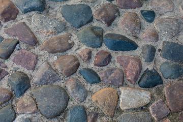 Abstract background of cobblestone pavement close-up. Top view on stone road close up. High resolution photo. Mock up or vintage grunge texture.