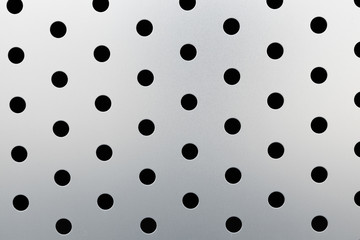 Rapid black dot pattern on gray background, round holes texture on perforated metal panel surface.