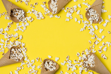 Fototapeta na wymiar Popcorns with waffle cones on yellow background with space for writing the text