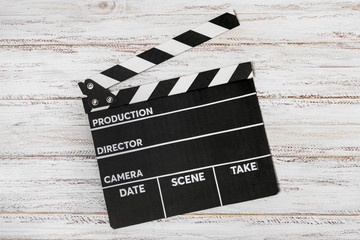 Obraz premium An elevated view on clapperboard over white wooden desk