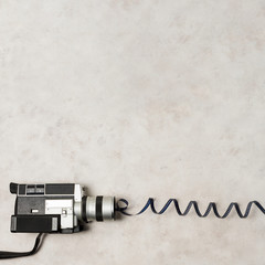 An overhead view of camcorder with swirl film stripes on grey concrete backdrop