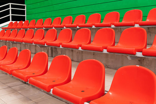 Rows of red diagonal spectator seats with no people in it