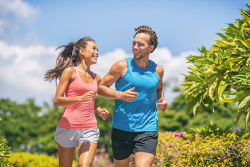 Active healthy runners couple running laughing talking together happy training buddy outside...