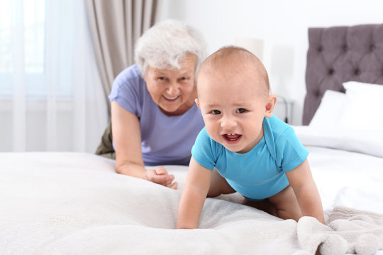Cute little baby with happy grandmother in bedroom