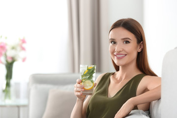 Young woman with lemonade at home. Refreshing drink