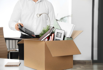 Young man packing stuff in box at office, closeup