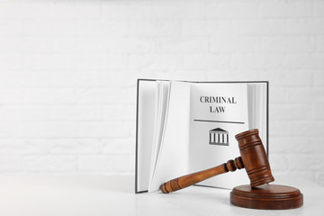 Book with words CRIMINAL LAW and gavel on table against white background. Space for text