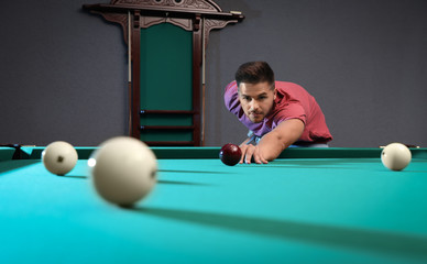 Fototapeta premium Handsome young man playing Russian billiard indoors