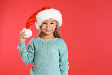 Happy little child in Santa hat on red background. Christmas celebration