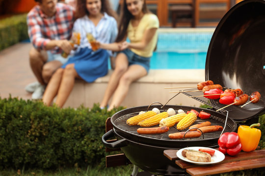 Barbecue grill with fresh food and blurred people on background