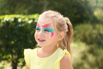 Cute little girl with face painting outdoors
