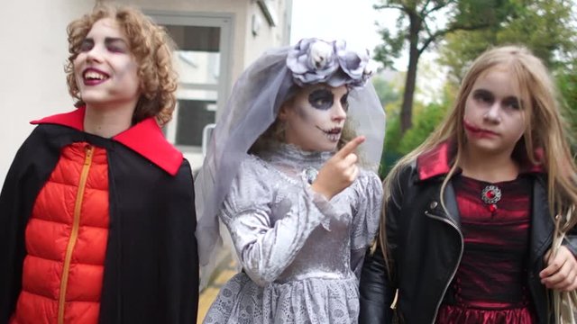 All Hallows Eve. Children in costumes and makeup of a dead bride and a vampire walk along the street celebrating Halloween