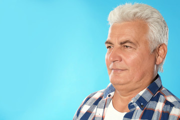 Mature man with double chin on blue background. Space for text