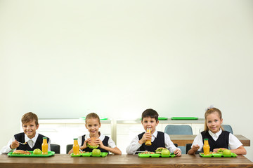 Happy children eating healthy food for lunch in school canteen