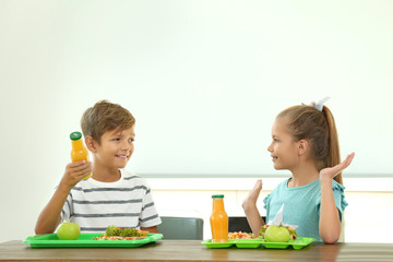 Happy children eating healthy food for lunch in school canteen