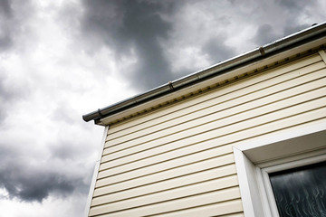 SIP panel house construction. Brown rain gutters. Drainage system with plastic siding and eaves on blue sky background.