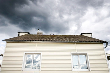 SIP panel house construction. Brown rain gutters. Drainage system with plastic siding and eaves on blue sky background.