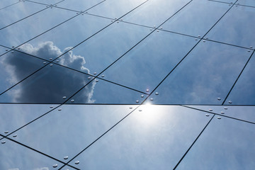 Glass surface on building facade with sky and sun rays reflection