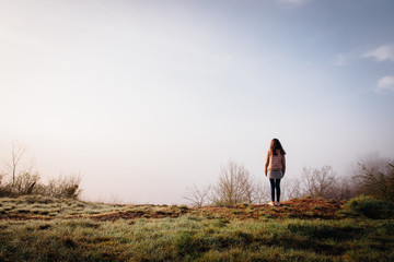 une jeune fille se prom&egrave;ne vers une falaise. Une femme regardant un paysage brumeux. Une adolescente vers une falaise et du brouilard.