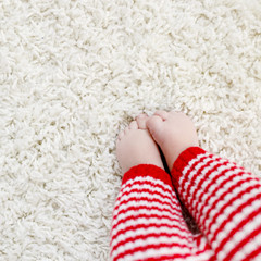 Close-up of baby body and legs in red Santa Clause trousers. New born child, little girl or boy. Kid having fun. Family, new life, childhood, holiday concept. Closeup for Christmas postcard.