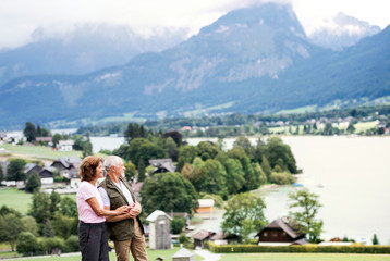 Fototapeta na wymiar A senior pensioner couple hikers standing in nature, resting.