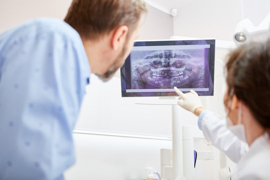 Zahnarzt erkl&auml;rt einem Patient R&ouml;ntgenaufnahme