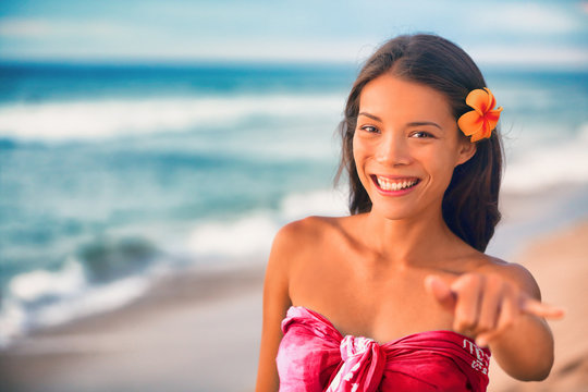 Hawaii hula dancer Asian woman on luau party on hawaiian beach doing shaka hand sign. ALOHA spirit.