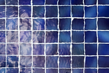 Blue tile on pool bottom under the water. Abstract background, soft focus
