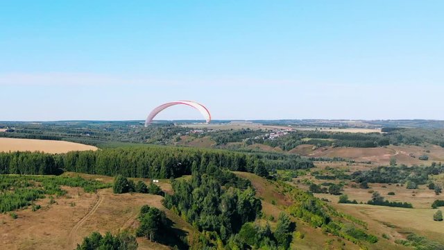 Paraglider is lowering and flying over the forest