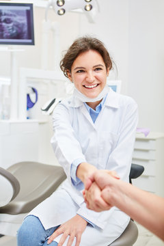 Freundliche Zahnärztin begrüßt Patient mit Handschlag