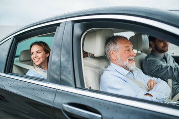 Multigeneration family sitting in car, driving and talking.