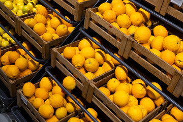 Diagonal view of wooden lug boxes with ripe lemons on counter in supermarket