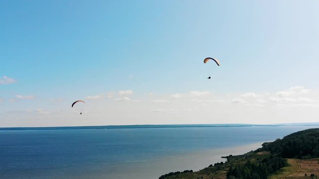 Vast waterscape with people flying around on paraplanes