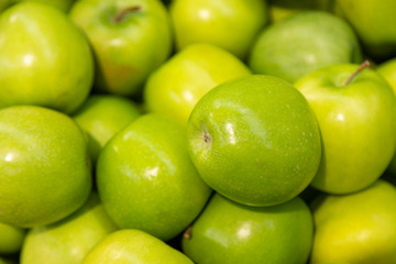 Green apple pile background at food farmer market close-up, healthy snack