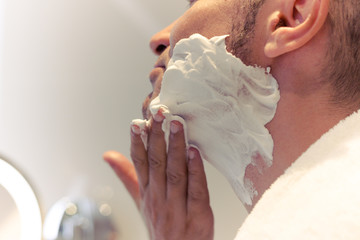 Close-up of man applying shaving cream on his face.