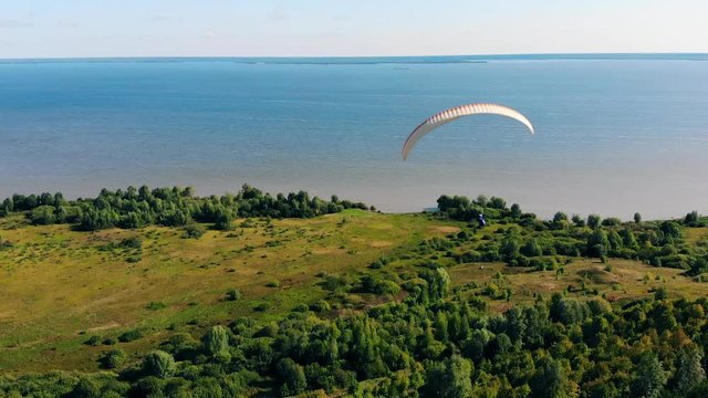 A couple is flying above the water on the parawing