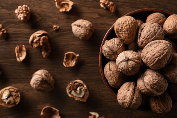  Walnuts nuts in a bowl on a dark brown wooden background in a dark key